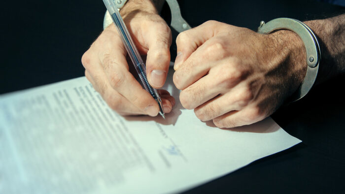 Person in handcuffs signing a statement