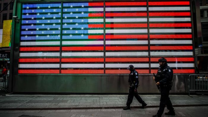 US flag with police walking in front