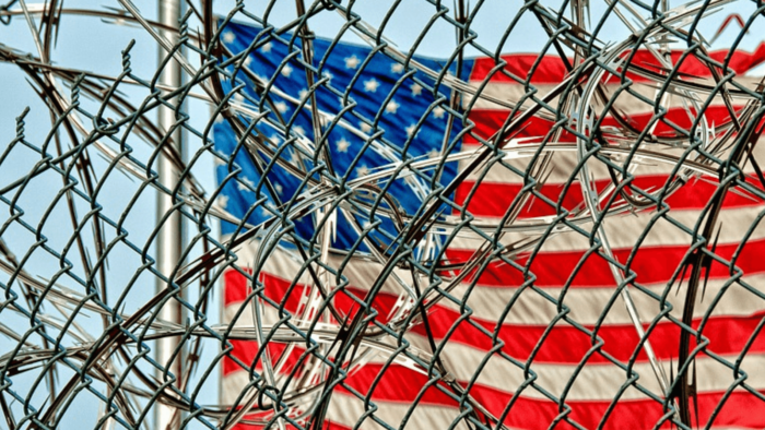 US flag behind barbed wire